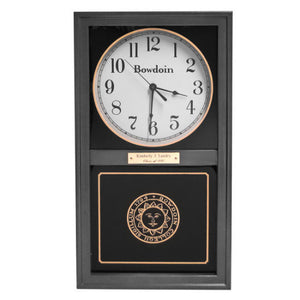 Black finish wall clock with clock face in upper inset in white with a Bowdoin wordmark and Arabic numerals, and a Bowdoin College seal in gold on the lower glass. Optional brass engraved plaque is shown on midrail.