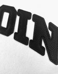 Closeup of black textured letters OIN on a white fabric background