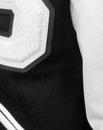 Detail of 3-layer terry applique B on chest of varsity jacket, showing texture of applique, leather sleeves, and wool body.