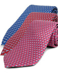 Three patterned ties, blue, red, and pink, on a white background