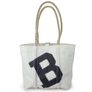 White bag with large black B patch on a tilted angle, natural hemp rope handles.