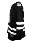 Side view of hockey jersey, showing white Bowdoin B embroidered on shoulder.