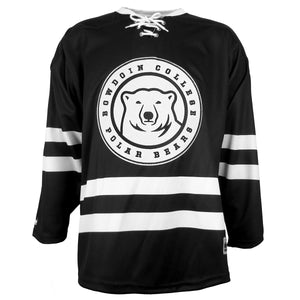 Black hockey jersey with white collar, white laces at throat, double white stripes on arms and lower torso. Large white patch applique with black embroidery of a mascot medallion surrounded by the words BOWDOIN COLLEGE POLAR BEARS.
