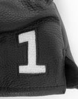 Closeup of needlepoint number 1 in black leather headcover.