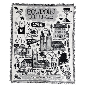 Black, white, and grey fringed tapestry blanket with illustrations of chickadee, Bowdoin Mascot, Bowdoin log dessert, Mass Hall, the Chapel, Walker Art, Hubbard Hall, the Hyde Plaza bear statue, and Schiller Coastal Studies.