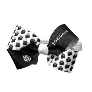 Baby headband with a large grosgrain bow in black and white. Black ribbon has opposite BOWDOIN and mascot medallion print. White ribbon has all-over paw prints. White satin elastic headband.