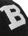 Closeup view of needlepointing on black hat.