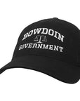 Black ball cap with white embroidery of BOWDOIN arched over a scale over GOVERNMENT