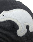 Closeup of white felt polar bear applique on black baseball hat.