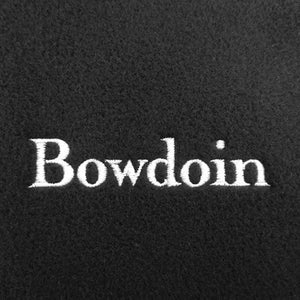 A closeup of black fleece with the word BOWDOIN embroidered on it in white.