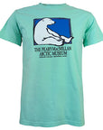Light aqua green short-sleeved T-shirt with picture of a polar bear sitting against the side of a rectangle with a blue background. Text beneath reads THE PEARY-MACMILLAN ARCTIC MUSEUM, BOWDOIN COLLEGE, BRUNSWICK, MAINE