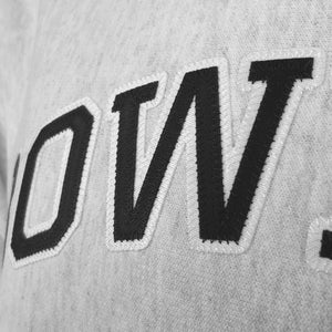 Closeup of silvery-gray heathered fleece showing detail of stitching on twill letters OW in black outlined with white.