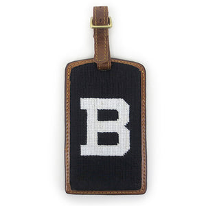 Brown leather luggage tag with brass buckle and needlepointed Bowdoin B backing.