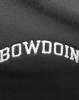 Closeup of white arched BOWDOIN embroidery on black polo shirt.