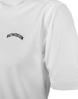 Closeup of white polo shirt showing black arched BOWDOIN embroidery on chest and silver UA logo on left sleeve.
