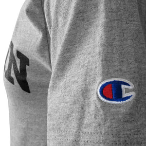 Closeup shot of the left sleeve of a short-sleeved Oxford heather gray T-shirt showing an embroidered Champion C logo patch in red, white, and blue.