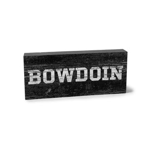 Grey wooden block with distressed white BOWDOIN imprint.