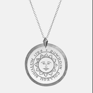 Round silver pendant with Bowdoin sun seal engraving.