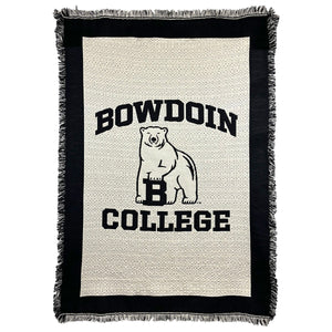 Ivory tapestry throw with fringe and black border. Black woven imprint of BOWDOIN arched over polar bear mascot over COLLEGE.