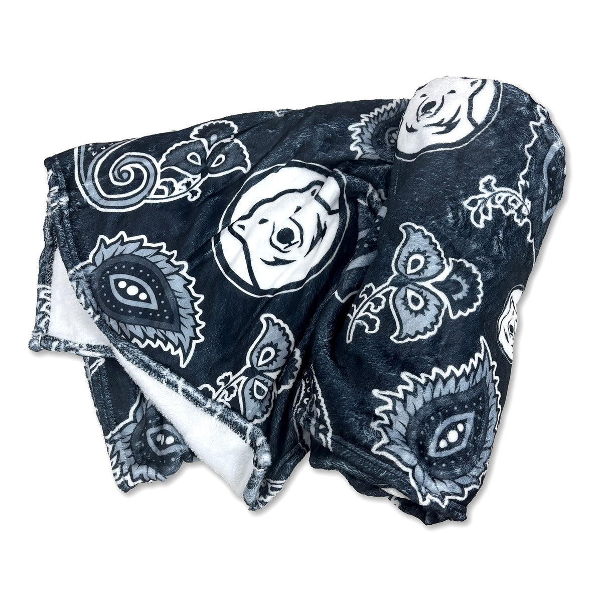A folded black plush blanket featuring a white and gray paisley bandana pattern with a polar bear face motif, showing a white plush on the reverse side.