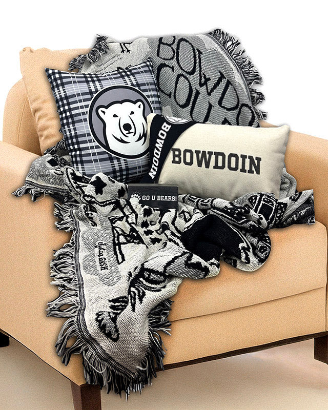 Collection of Bowdoin-themed pillows and blankets on a beige armchair.