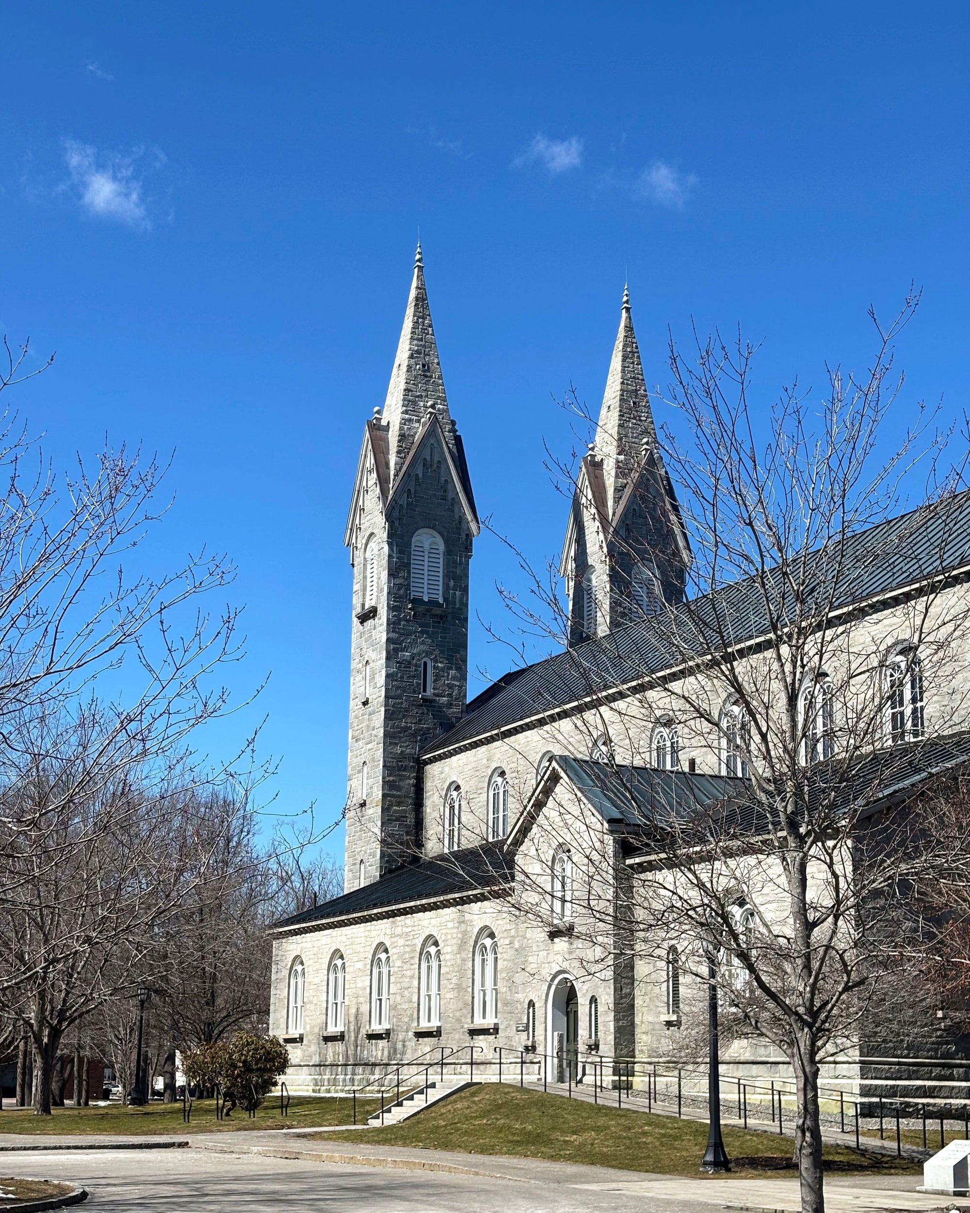 Large stone chapel with two tall spires under a clear blue sky.