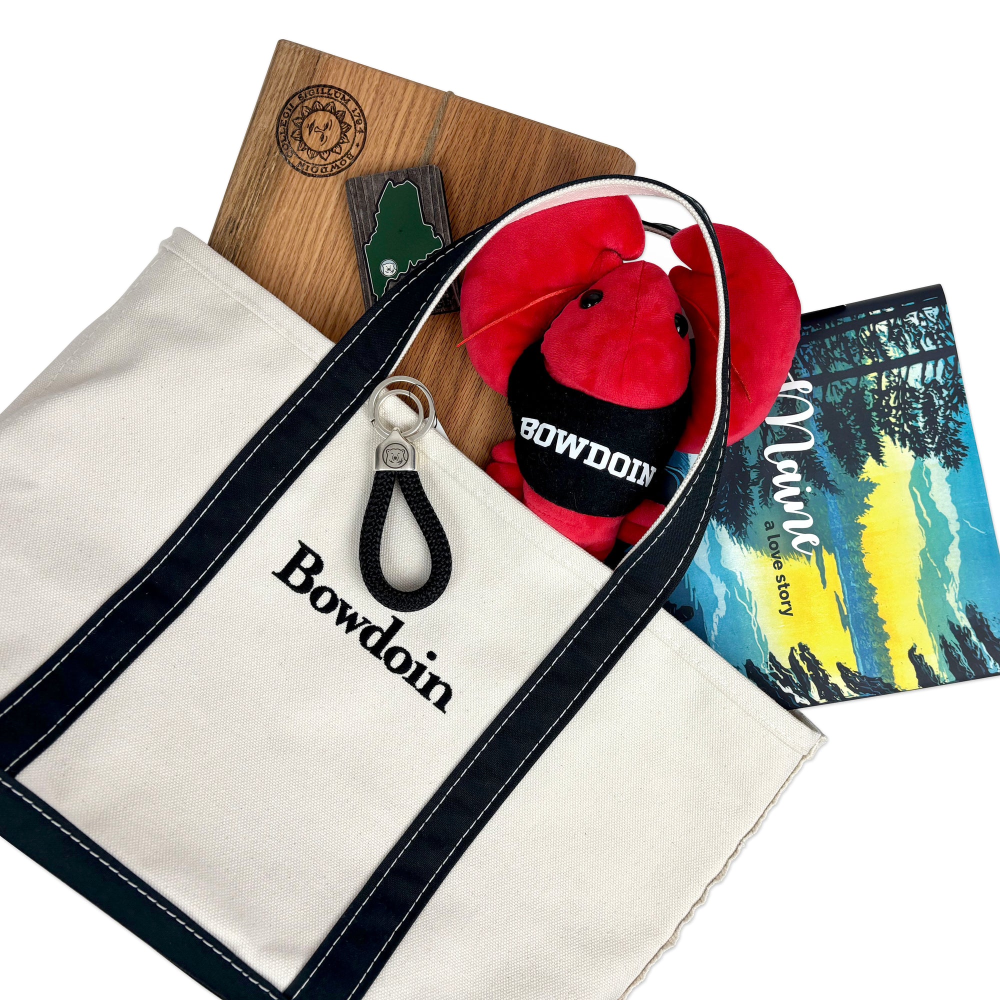 L.L.Bean Boat & Tote Bag containing a plush lobster, a Maine magnet, a key chain, a cutting board, and the book Maine, A Love Story.