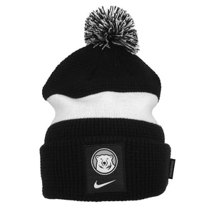 Black waffle-knit hat with white stripe and black and white pom. Black patch with mascot medallion and white Nike Swoosh beneath.