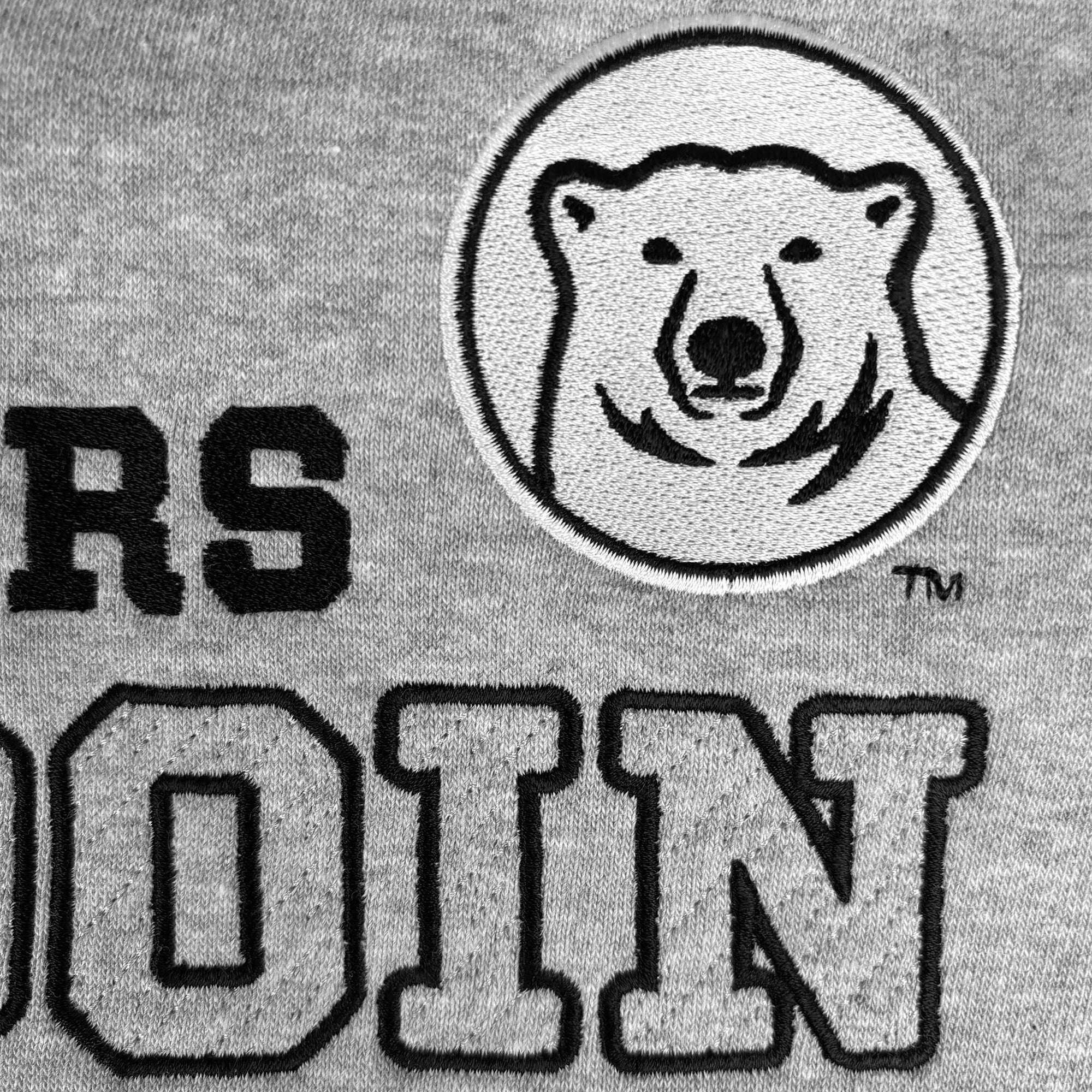 Close-up of a gray heather fabric with black embroidered text and a circular polar bear logo patch.
