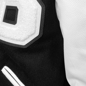 Detail of 3-layer terry applique B on chest of varsity jacket, showing texture of applique, leather sleeves, and wool body.