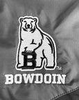 Close-up of an embroidered Bowdoin bear logo with a large black letter B on a gray fabric background.