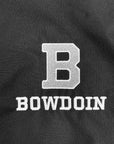 Close-up of a black fabric surface with a large white embroidered letter B above the word BOWDOIN in white embroidered block letters.
