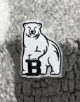 Embroidered patch of a bear with a 'B' on a textured fabric background