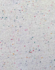 A close-up of an off-white knit fabric with a scattered confetti speckle pattern in multiple colors including pink, blue, orange, and green.