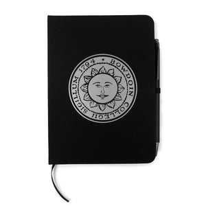 Black bound journal with silver imprint of Bowdoin sun seal.