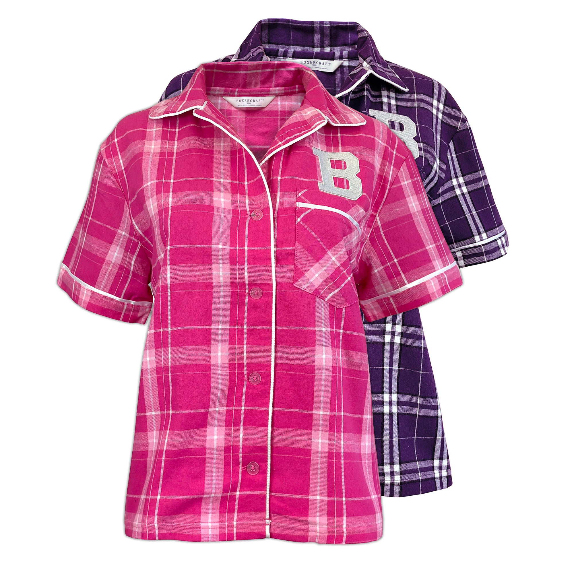 Two short-sleeve plaid button-up shirts shown on a white background, with a pink shirt in front and a purple shirt behind it. Both shirts feature a large letter 'B' on the chest and white piping along the collar, placket, and sleeve cuffs.