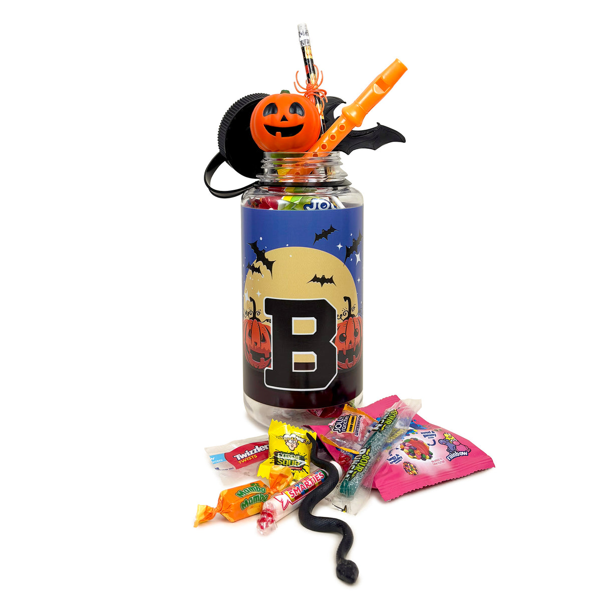 A Halloween-themed water bottle with a clear plastic body, a blue and black label featuring a large letter 'B', and a jack-o'-lantern decoration on top. The jar is filled with colorful candies and surrounded by assorted sweets on a white background.