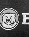 Close-up of a black knit fabric featuring a white embroidered polar bear face inside a circular patch and a large white embroidered letter B.