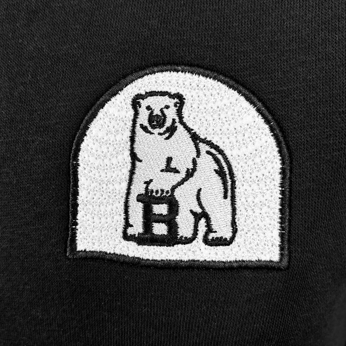 Closeup of arched white embroidered polar bear patch.