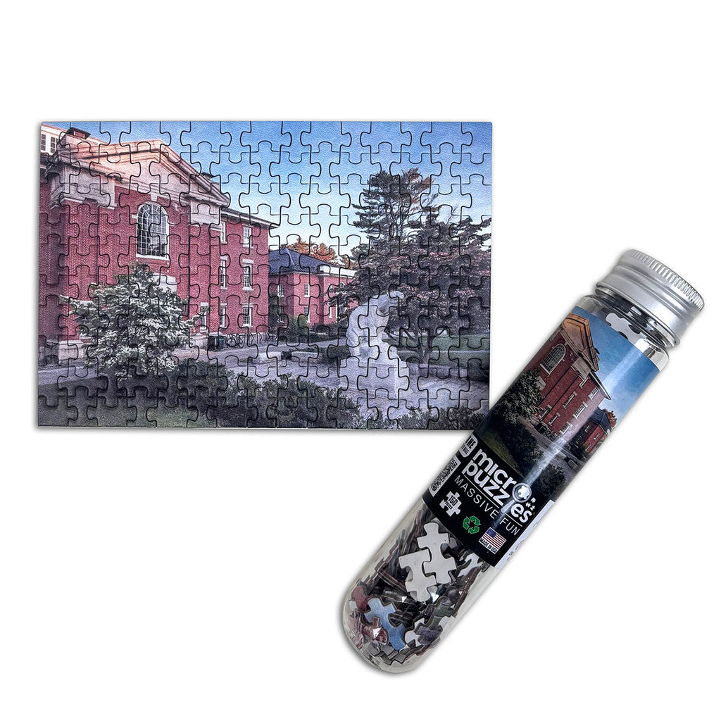 Photo of completed postcard-sized puzzle with picture of Hyde Plaza on Bowdoin campus, and its accompanying test tube container.