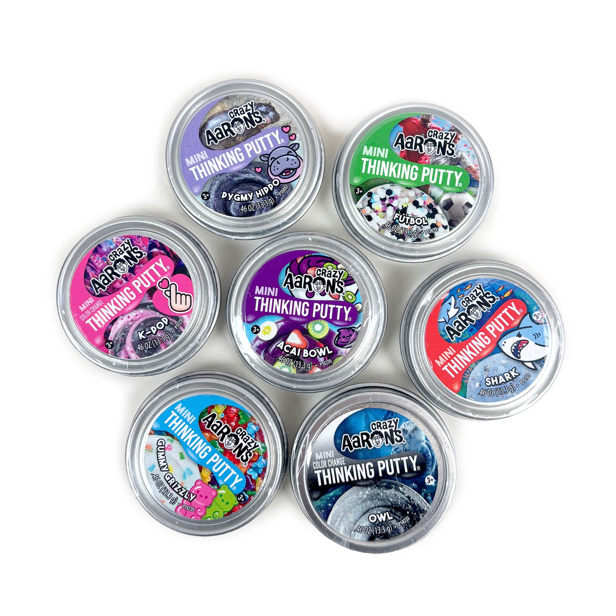 Set of mini thinking putty containers with colorful labels on a white background
