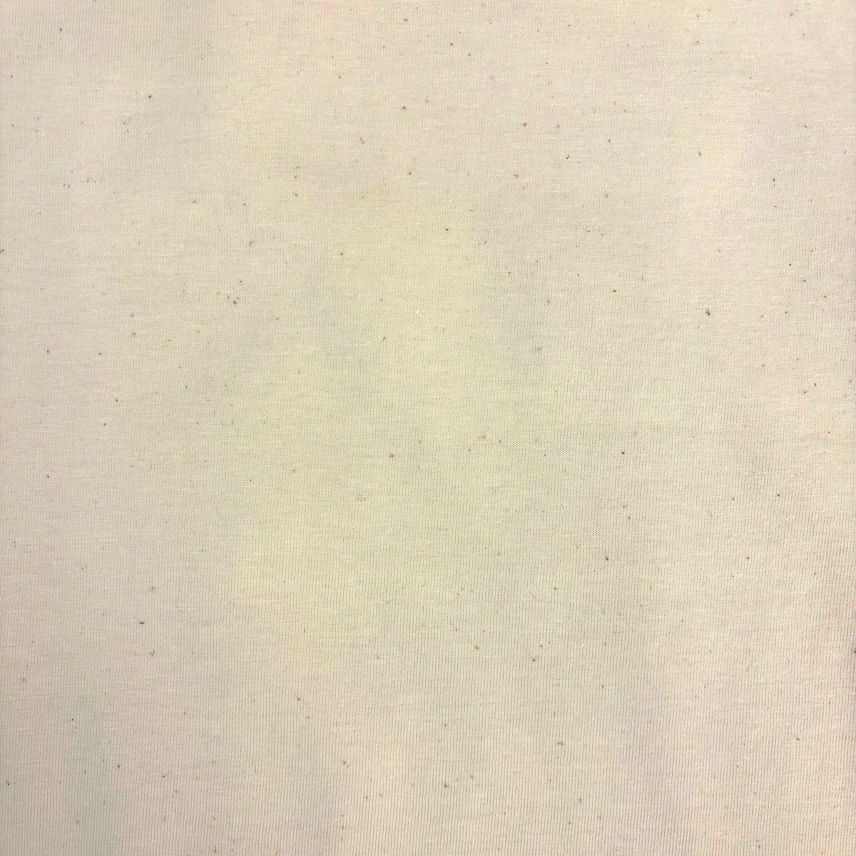 A close-up of a light cream or off-white textured fabric with subtle speckles and a fine woven pattern.