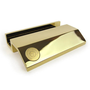 Gold tone metal business card holder with small engraved Bowdoin sun seal on right hand side.