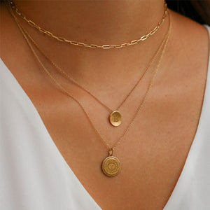 White woman wearing a plain gold chain necklace, a Bowdoin B Petite necklace, and a Bowdoin Seal Sunburst necklace.