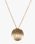 Gold necklace with slightly concave gold pendant engraved with the Bowdoin College seal.