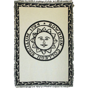 Ivory tapestry throw blanket with fringe. Black border with ivory vines. Large black imprint of Bowdoin sun seal in center.