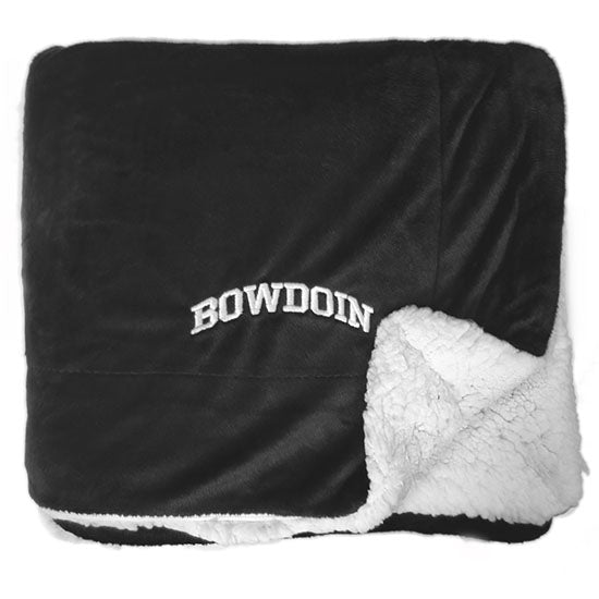 Black plush blanket with white arched BOWDOIN embroidery in corner and white faux-sherpa on the reverse.