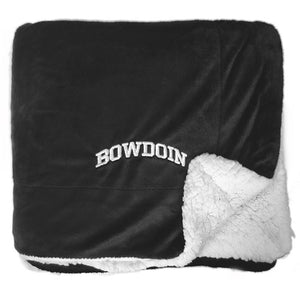 Black plush blanket with white arched BOWDOIN embroidery in corner and white faux-sherpa on the reverse.
