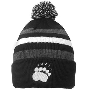 Black hat with alternating grey and white stripes. Black, white, and grey pom. White paw print patch on cuff of hat.