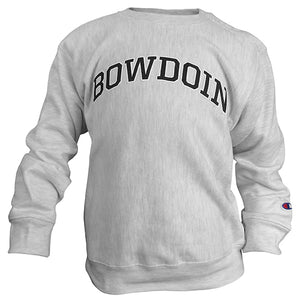 A photo of a children's crewneck sweatshirt in silver heather. There is a small Champion C logo patch in red white and blue on the left sleeve just above the cuff. The word BOWDOIN is imprinted in an arch across the chest in black with a white stroke outline.